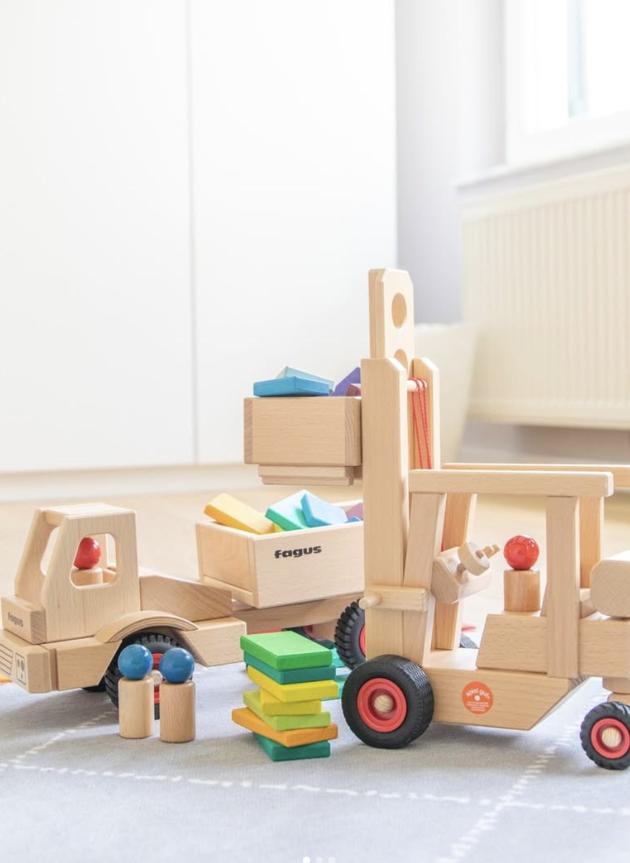 Fagus gaffeltruck løfter en kasse med klosser, lastebil og figurer ved siden av